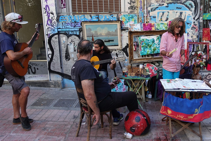 People sitting on a street with graffiti in the background