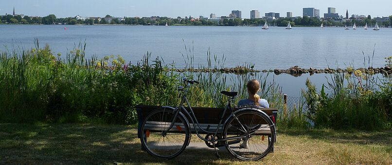 woman with bike on bench by the river