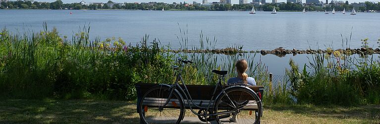 woman with bike on bench by the river