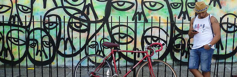 man standing next to bike before graffiti wall