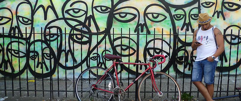 man standing next to bike before graffiti wall